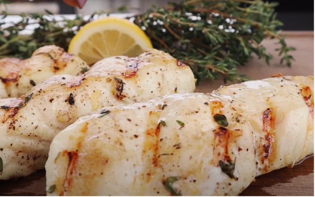 A close-up shot of a perfectly grilled halibut fillet, seared to a golden-brown crust, resting atop a charcoal grill grate. The fish glistens with a light coating of olive oil, its tender white flesh flaking away at the touch of a fork. Vibrant green herbs, such as fresh dill and parsley, are scattered around the edges, adding a pop of color and a hint of fragrance. The image is illuminated by warm, natural lighting, casting a soft, inviting glow over the scene. The background is slightly blurred, emphasizing the focus on the expertly prepared halibut. An overall impression of effortless culinary mastery and the mouthwatering anticipation of a delicious summer grilled dish. A close-up shot of a perfectly grilled halibut fillet, seared to a golden-brown crust, resting atop a charcoal grill grate. The fish glistens with a light coating of olive oil, its tender white flesh flaking away at the touch of a fork. Vibrant green herbs, such as fresh dill and parsley, are scattered around the edges, adding a pop of color and a hint of fragrance. The image is illuminated by warm, natural lighting, casting a soft, inviting glow over the scene. The background is slightly blurred, emphasizing the focus on the expertly prepared halibut. An overall impression of effortless culinary mastery and the mouthwatering anticipation of a delicious summer grilled dish.