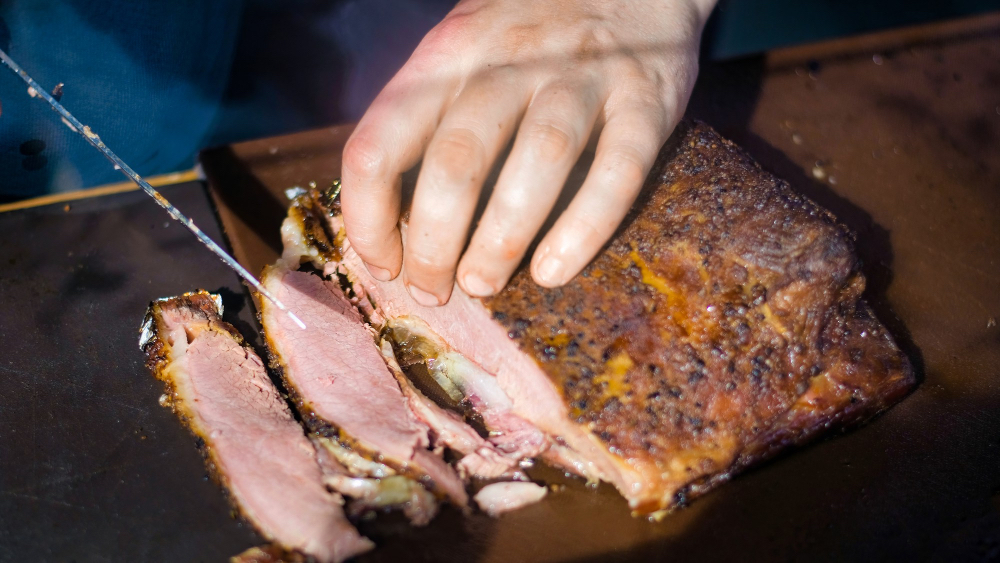 A mouthwatering smoked brisket recipe, perfectly executed on a pellet grill. In the foreground, a thick, juicy slab of brisket, its exterior glistening with a deep mahogany-colored bark, while the interior reveals tender, succulent meat. Wisps of fragrant smoke curl around the brisket, hinting at the complex flavors infused during the long, slow cooking process. The middle ground showcases the pellet grill, its sleek stainless-steel exterior complemented by the warm, amber glow of the burning hardwood pellets. In the background, a rustic, weathered wooden table, setting the scene for this hearty, satisfying main course. The lighting is soft and natural, casting a gentle spotlight on the star of the dish, while the overall mood is one of rustic elegance and mouthwatering anticipation. smoked brisket