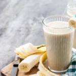 Image of a classic banana smoothie in a tall glass with a sprinkle of cinnamon on top.