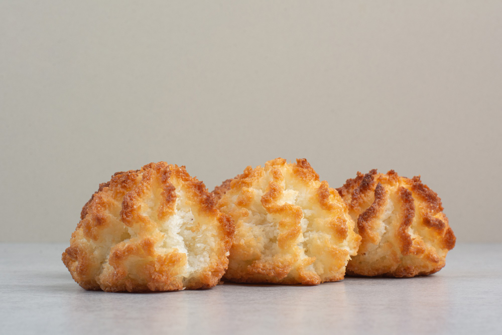 Image of coconut macaroons on a baking sheet, with some dipped in chocolate. milk free desserts