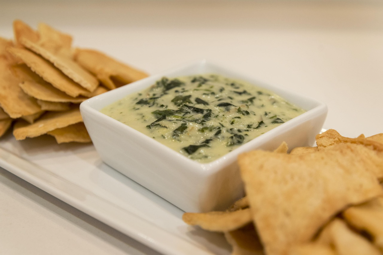 A delectable crockpot spinach and artichoke dip, gently simmering in a rustic earthenware bowl. The creamy, melted cheese blends seamlessly with the vibrant green spinach and tender artichoke hearts, creating a tempting, mouth-watering visual. Soft, golden-brown crackers or slices of crusty bread sit nearby, ready to be dipped into the rich, indulgent mixture. Warm, ambient lighting casts a cozy glow, setting the scene for effortless entertaining. The composition is balanced, with the dip taking center stage, surrounded by complementary elements that showcase its irresistible texture and flavor. An inviting, comforting scene that captures the essence of this crockpot spinach artichoke dip variation. spinach and artichoke dip